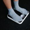Close-up of feet in socks standing on a scale, focusing on weight measurement.